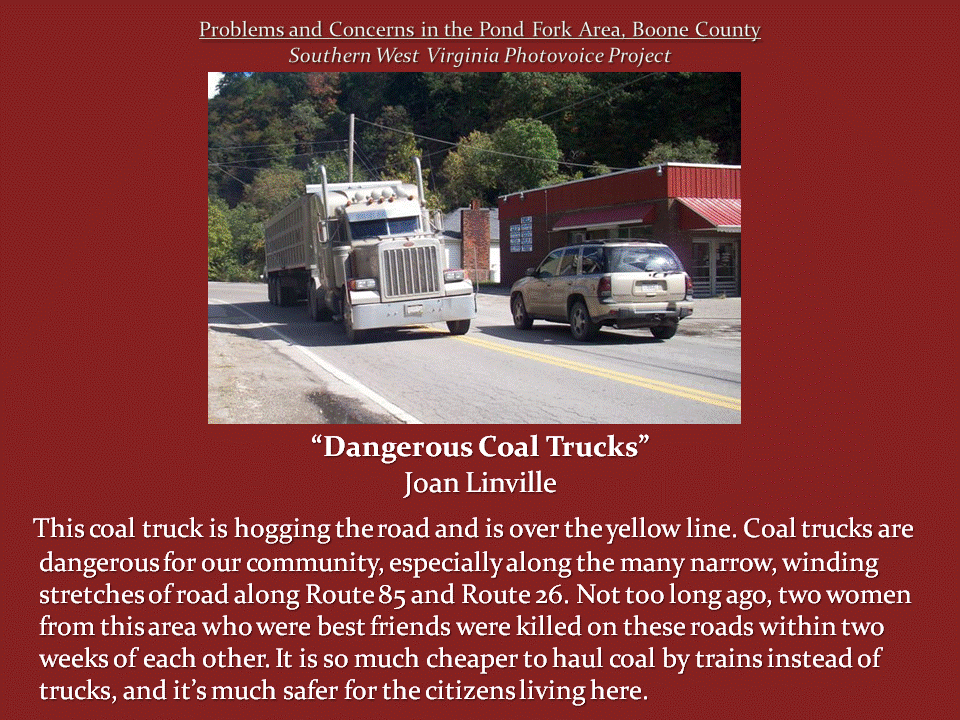 A large coal-hauling truck crosses the yellow centerline on a narrow road beside an SUV and a brick storefront.