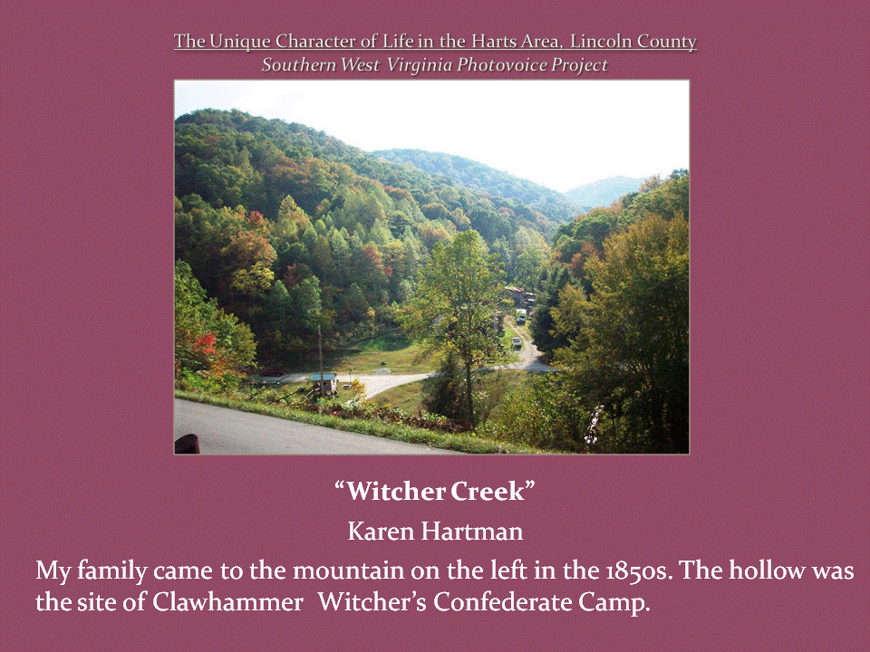 A winding road passes through a green valley surrounded by densely wooded mountains.