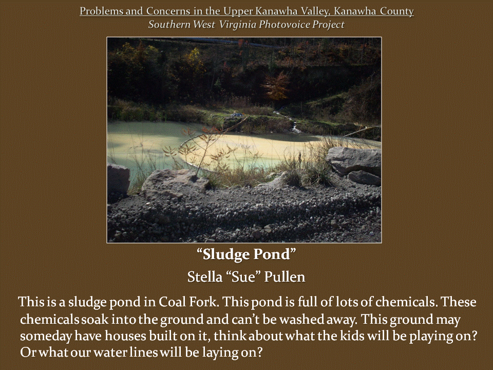 Pond filled with murky, pale green water, surrounded by gravel, large rocks, sparse vegetation, and wooded hillsides.