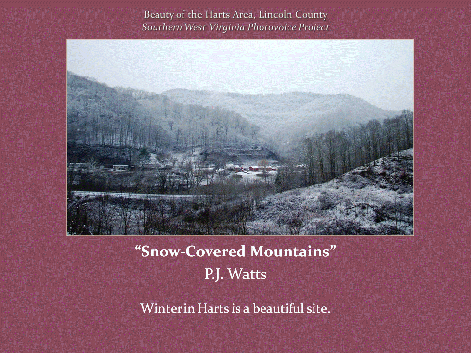 Snow-covered mountains and bare winter trees surround a small rural community nestled in a valley.