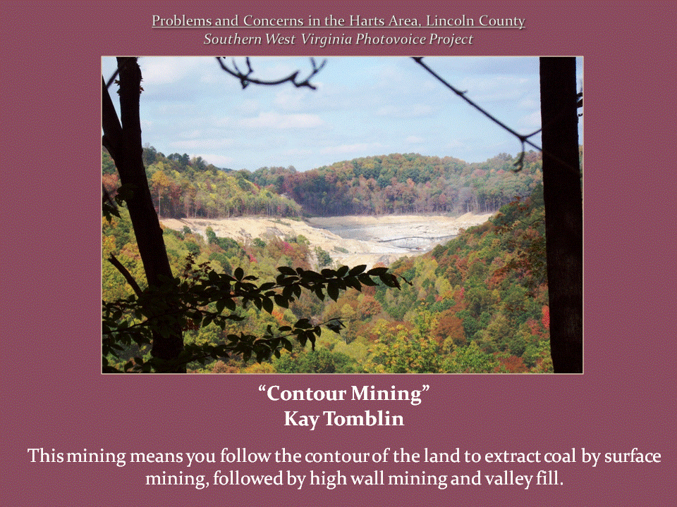 A large, exposed surface-mining area cuts across a forested mountainside surrounded by autumn foliage.
