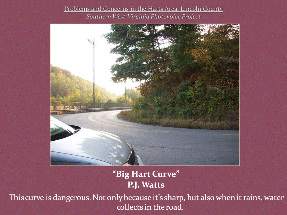 A sharp bend in a paved mountain road bordered by a guardrail and dense vegetation.