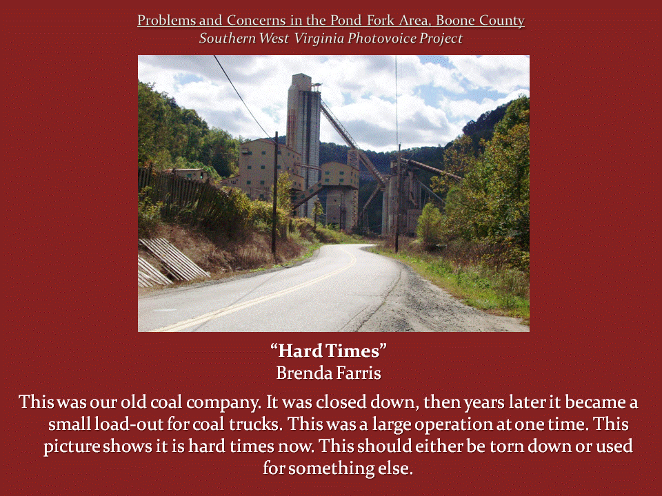 A curving two-lane road leads toward a large, closed coal-processing facility with tall industrial towers and conveyors.